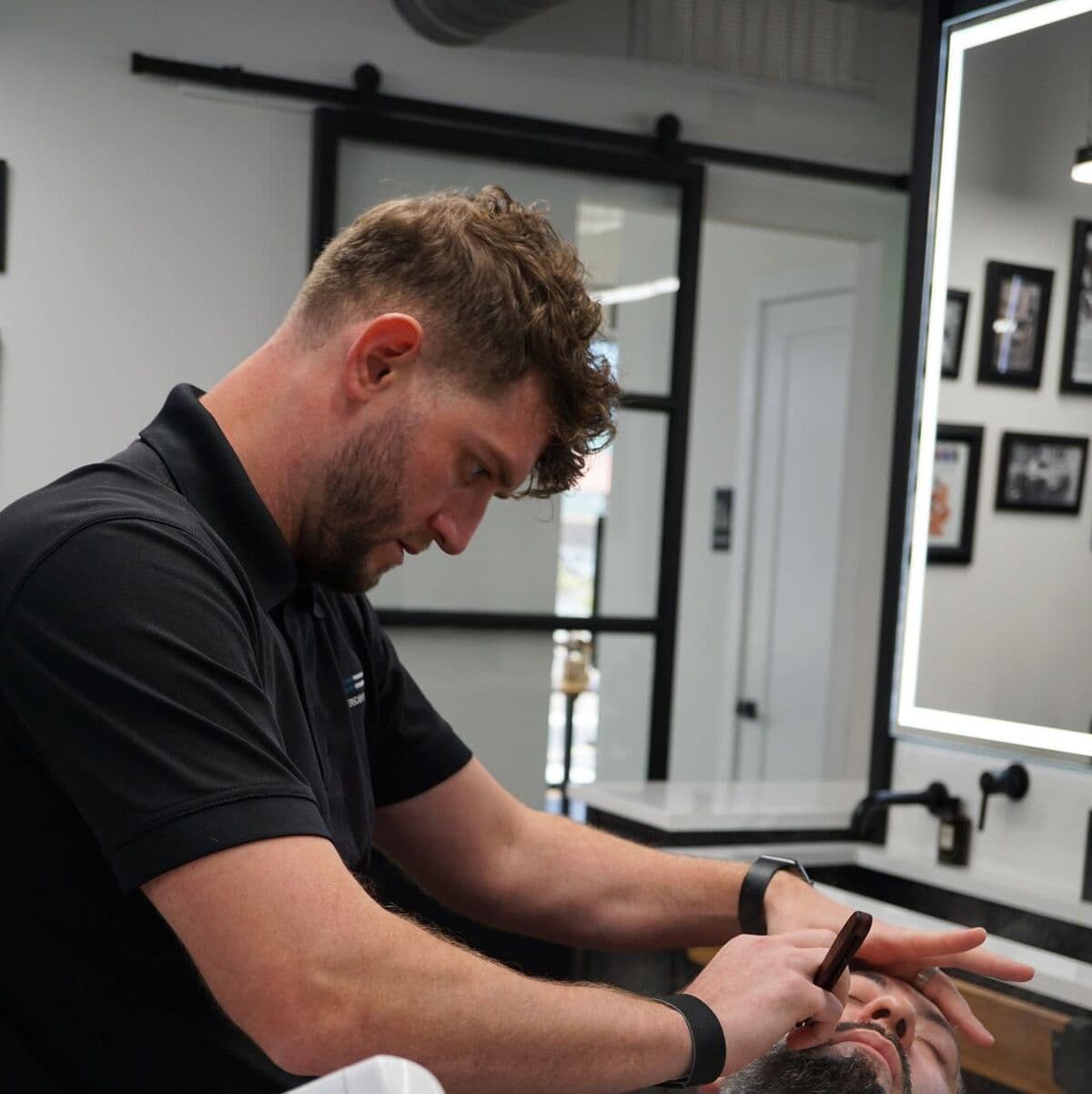 Andy working on a client's beard with a razor