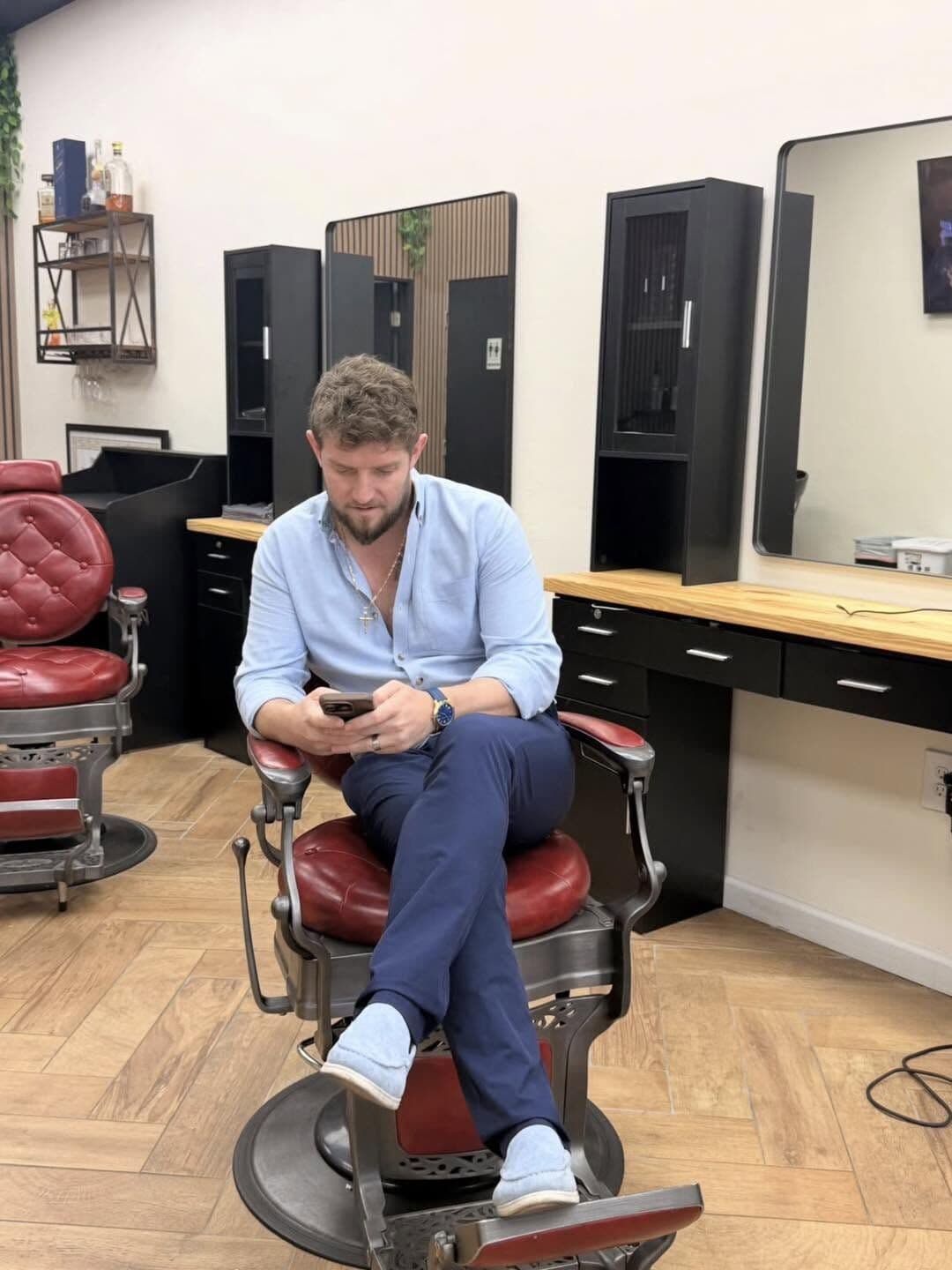 Andy Peto, the owner, checking his phone in one of the red barber chairs