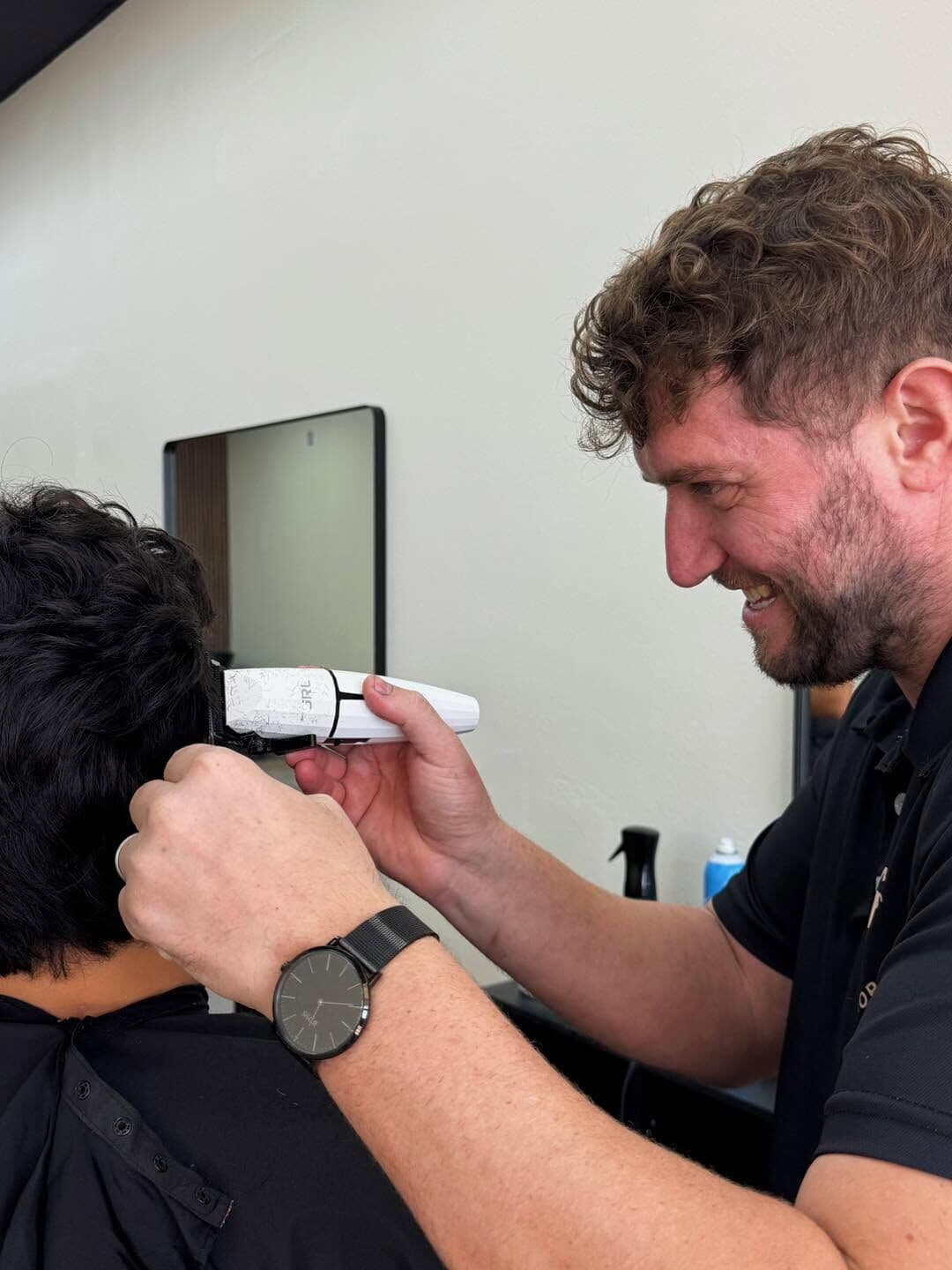 Andy Peto taking clippers to the back of a client's dark hair