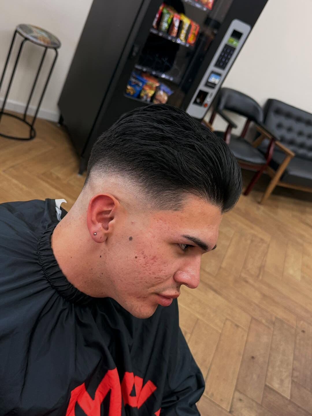 A low fade with the top slicked back, seen from the side