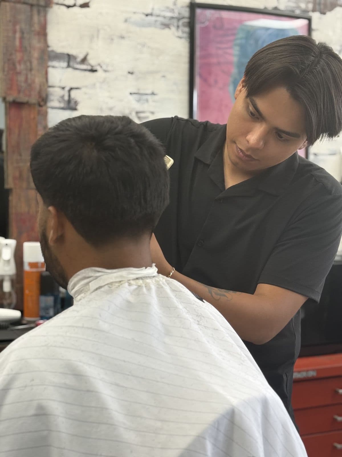 A barber cleaning up the back of a client's haircut