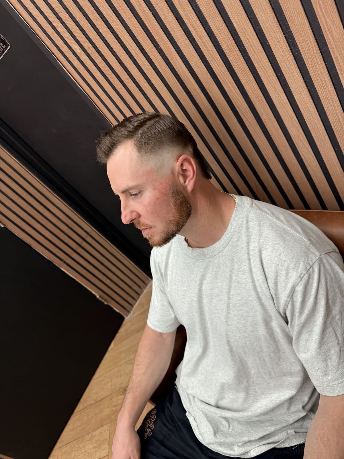 A client with a short fade and a trimmed beard, in profile