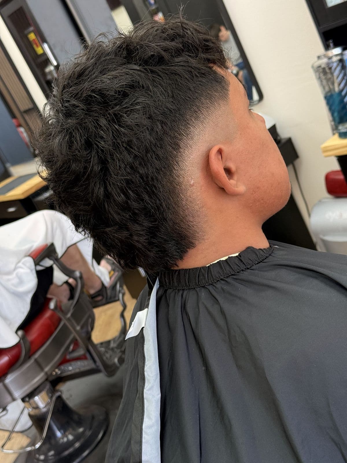 A taper fade with curls left long on top, from behind