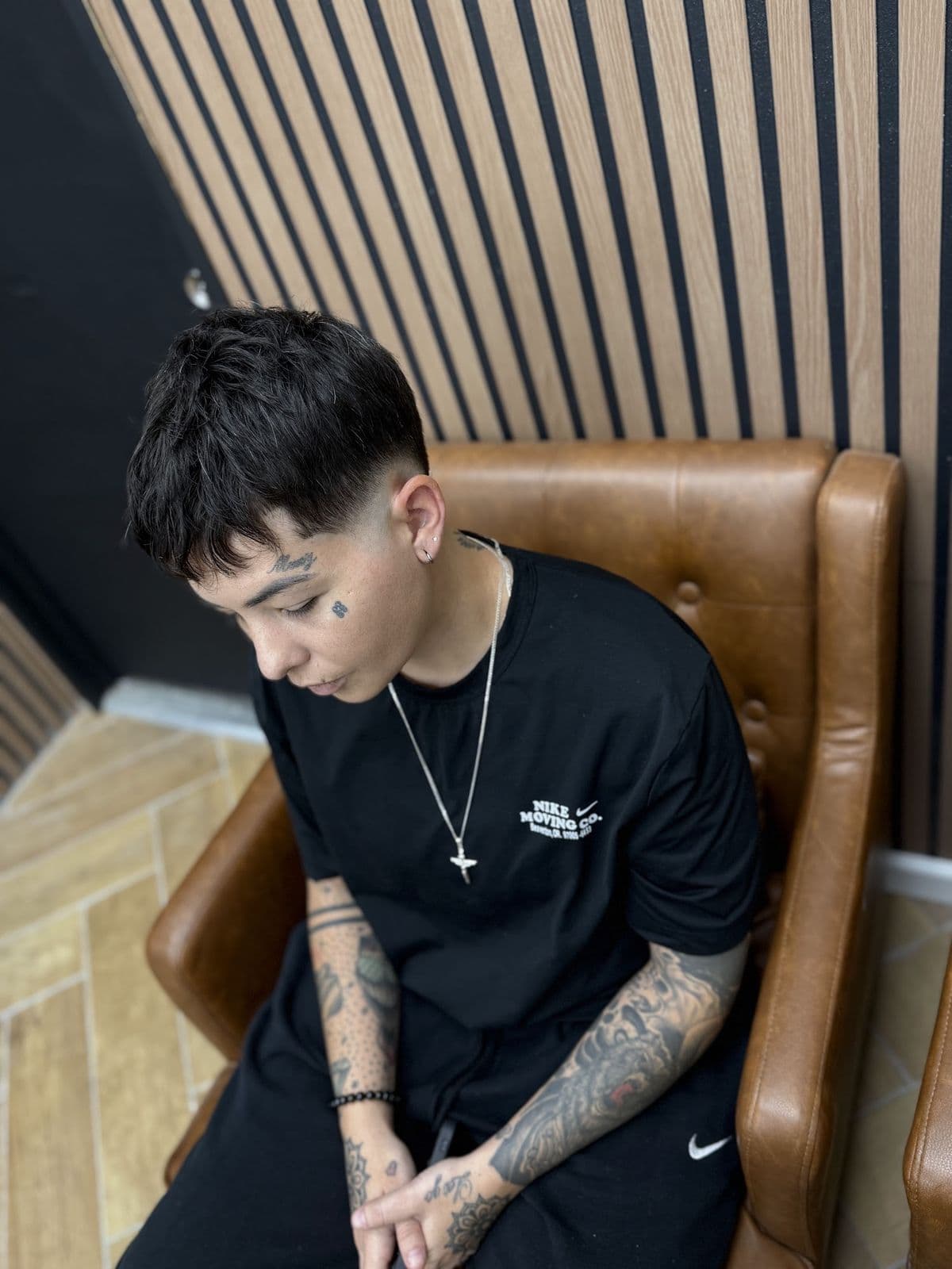 A client with a textured fringe and a fade, seated in a leather armchair