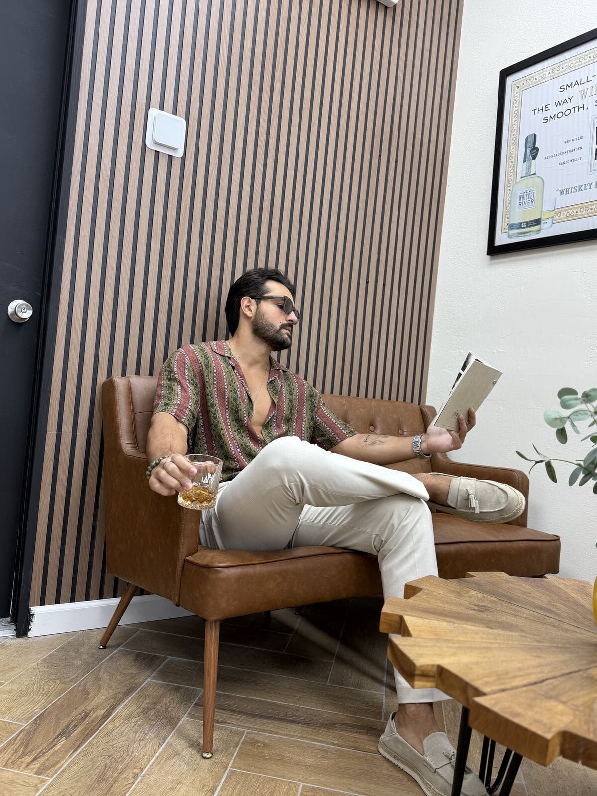 A client reading in a leather chair against the wood-slat wall