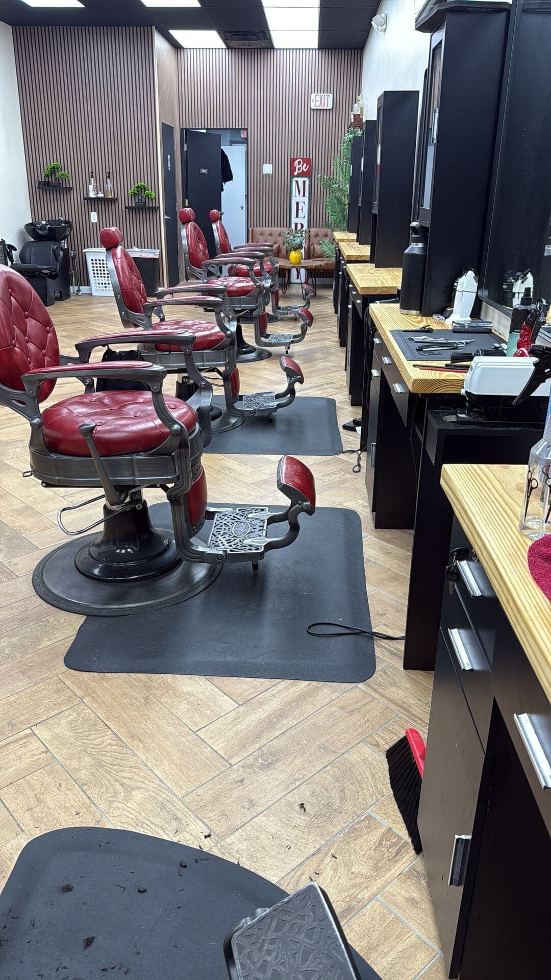 A row of red vintage barber chairs on the herringbone floor at The Men's Barbershop